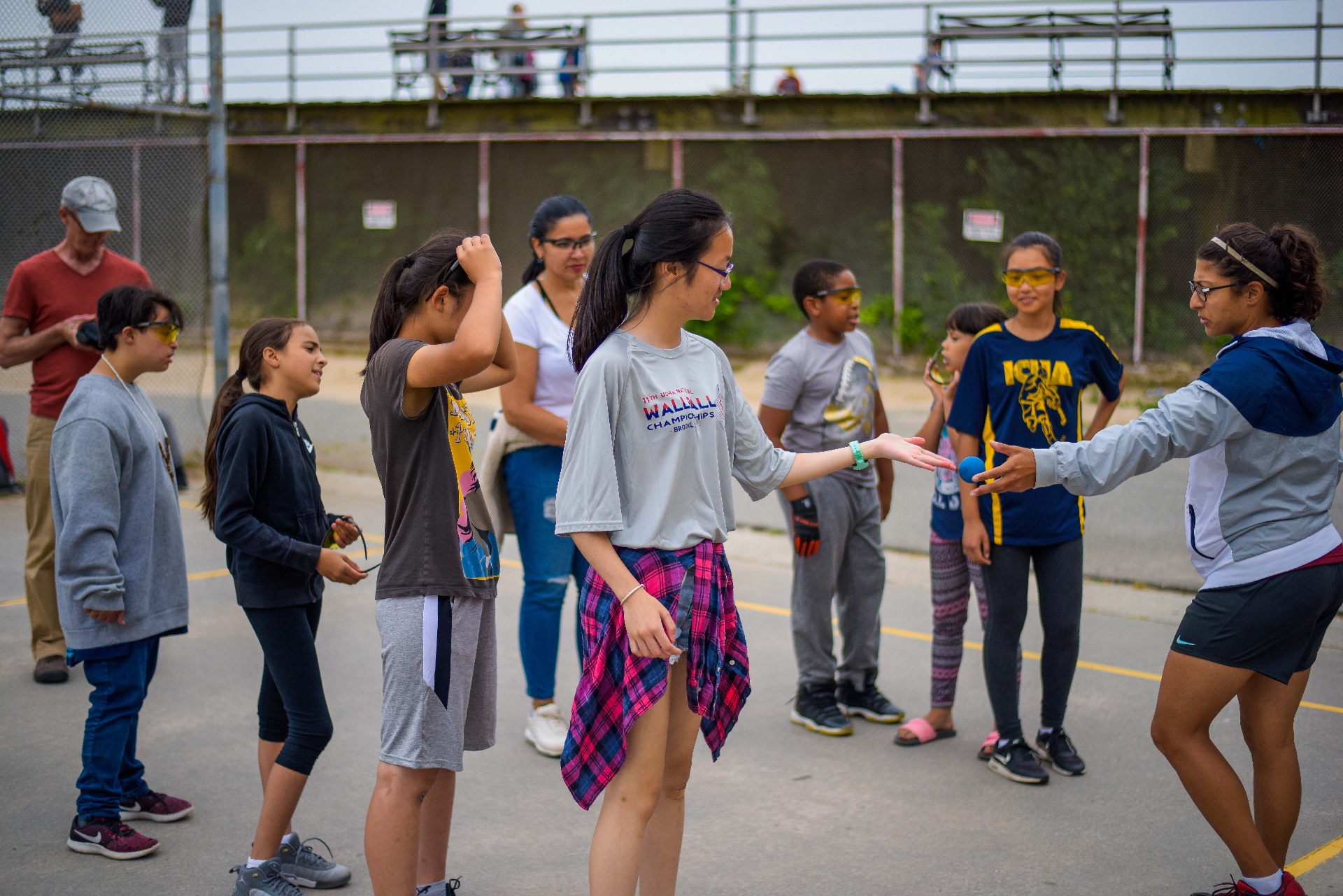 Coach teaching a group of kids the basics of handball on an outdoor court